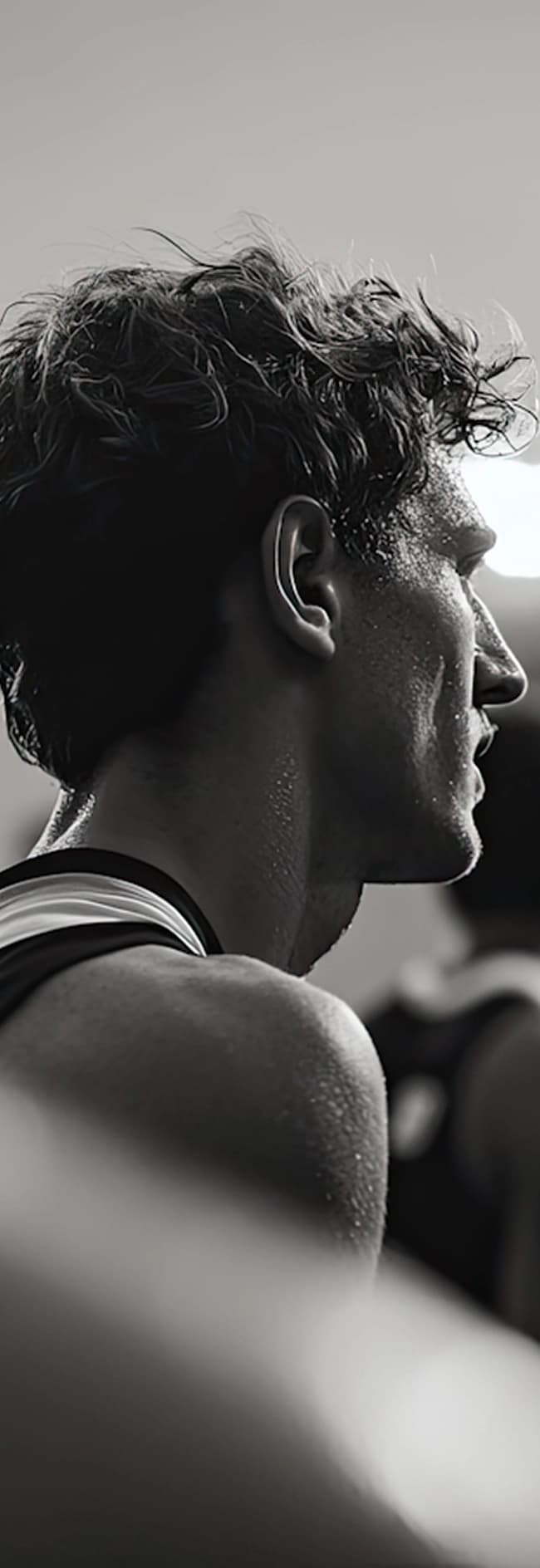 A man wearing a black tank top stands confidently, showcasing a casual and athletic style.